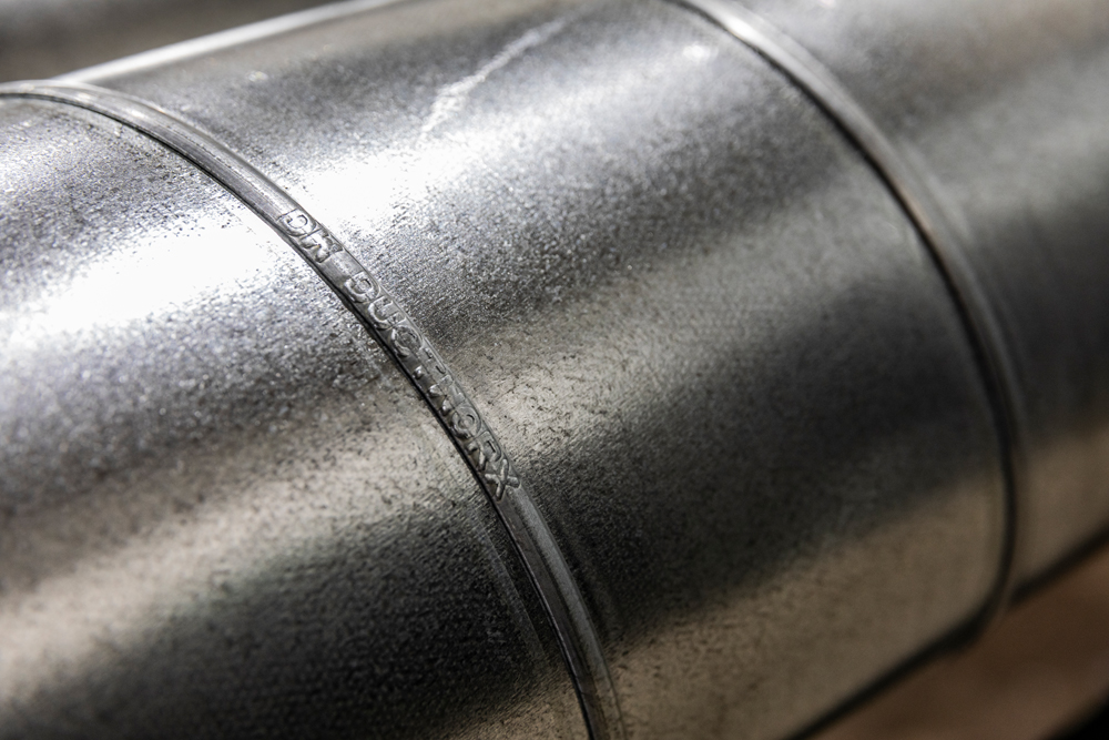 Close-up of spiral ductwork with embossed DuctWorx branding, showcasing high-quality galvanized construction for durable, leak-resistant HVAC duct systems.