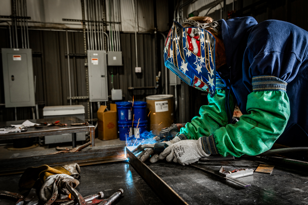 A skilled DuctWorx fabricator welding a custom ductwork component in the fabrication shop, showcasing precision craftsmanship and dedication to high-quality HVAC solutions.