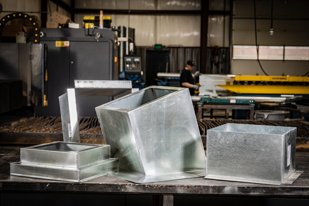 A set of custom roof curbs and rectangular duct fittings fabricated by DuctWorx for complex HVAC installations, including pitched and offset applications.