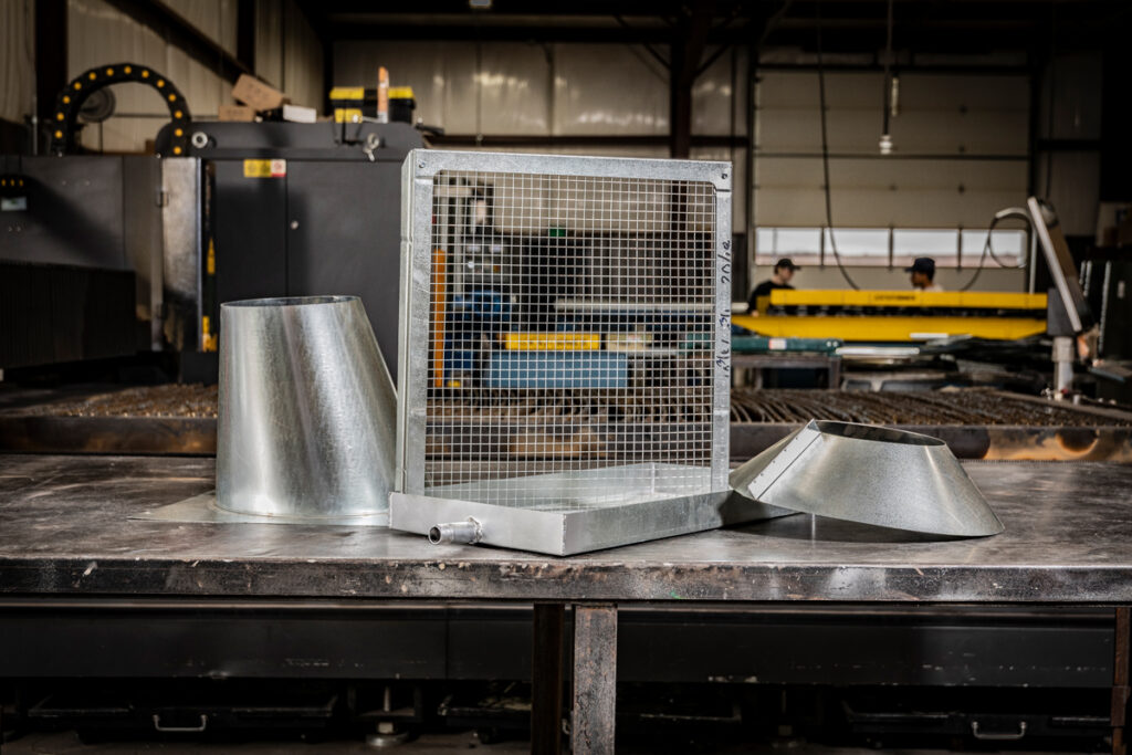Custom-fabricated roof penetration flashings and a galvanized ventilation screen from DuctWorx, engineered for precise HVAC integration and durable weather-resistant performance.